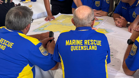 Volunteers in MRQ shirts sitting around a table looking at maps