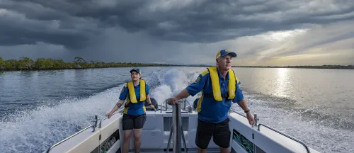 MRQ volunteers aboard a vessel looking ahead as they sail away from the sunset.